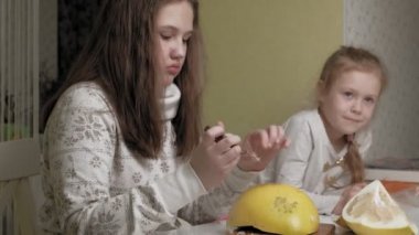 İki kız kardeş pomelo yiyor.