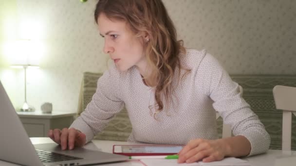 Uma jovem trabalha em um computador em casa . — Vídeo de Stock