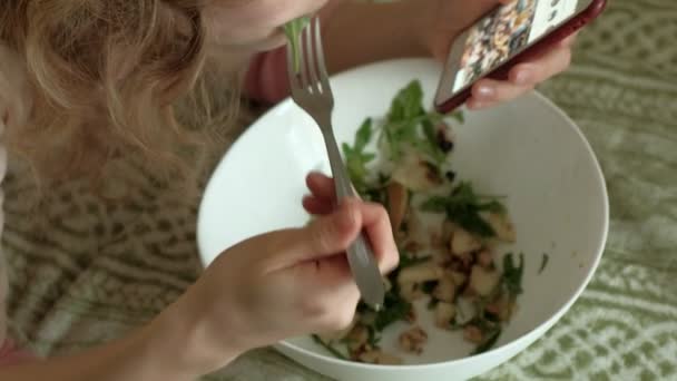 Mujer joven acostada en un sofá ensalada rúcula . — Vídeo de stock