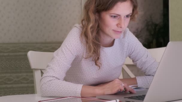 Μια νεαρή γυναίκα δουλεύει σε έναν υπολογιστή στο σπίτι.. — Αρχείο Βίντεο