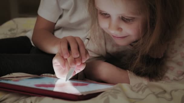 Filhinhos, irmão e irmã estão deitados na cama e brincando no tablet antes de ir para a cama . — Vídeo de Stock