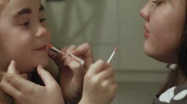 Elbiseli kız kardeşi olan neşeli bir çocuk birbirlerine makyaj yapar..