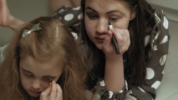 Fröhliches Kind mit Schwester in Kleidern schminken sich gegenseitig. — Stockvideo