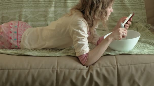Junge Frau liegt auf einem Sofa Rucolasalat. — Stockvideo