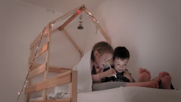 Gyermekek használják a tablettát, miközben feküdt az ágyban — Stock videók