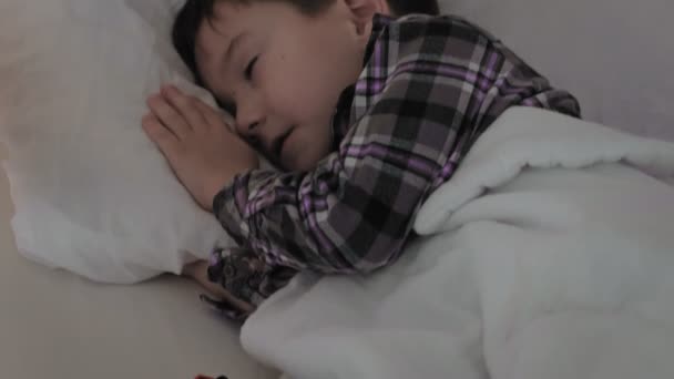 El niño yace en la cama, el insomnio, el sueño pobre — Vídeo de stock