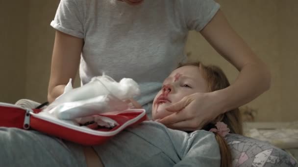 Mãe fornece primeiros socorros para uma criança com um nariz sangrento . — Vídeo de Stock