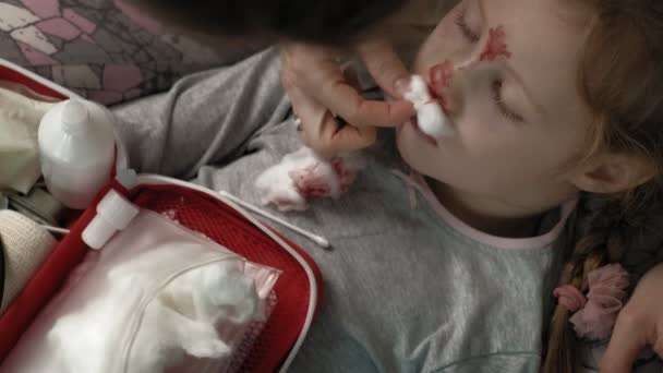 Maman fournit les premiers soins à un enfant avec un nez sanglant . — Video