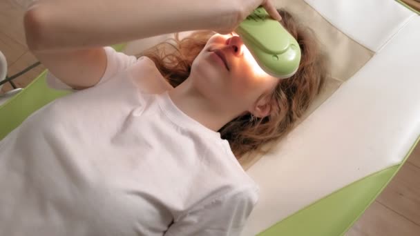 Kobieta leży na łóżku do masażu z jadeitowymi rolkami. — Wideo stockowe