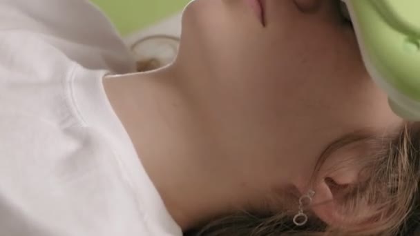 Kobieta leży na łóżku do masażu z jadeitowymi rolkami. — Wideo stockowe