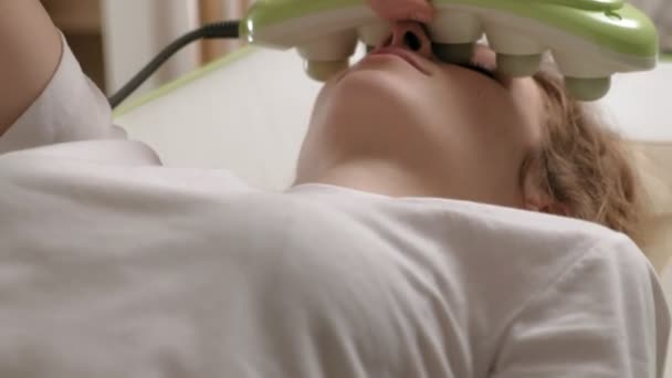 Une femme se couche sur un lit de massage avec des rouleaux de jade . — Video