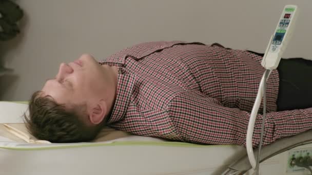 Un hombre se acuesta en una cama de masaje con rodillos de jade . — Vídeo de stock