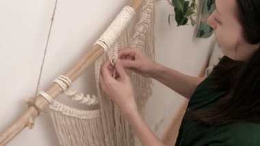 Kadın çubuğa makrome örüyor..