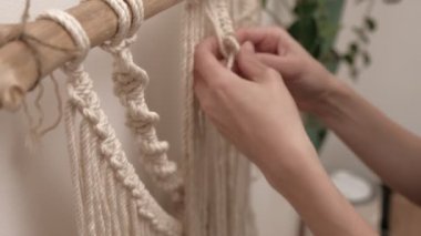 Kadın çubuğa makrome örüyor..