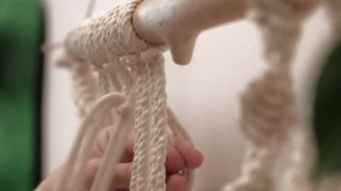 Kadın çubuğa makrome örüyor..