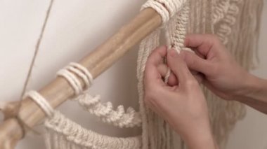 Kadın çubuğa makrome örüyor..