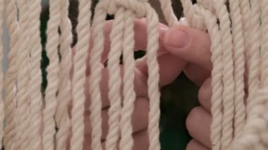 Kadın çubuğa makrome örüyor..