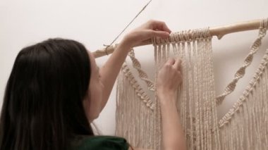 Kadın çubuğa makrome örüyor..