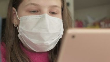 Coronavirus salgını sırasında evde çalışan maskeli bir kız.