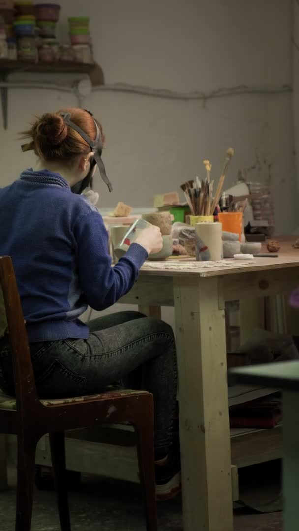 Ceramista feminina pinta um produto de barro.. Vídeo vertical — Vídeo de Stock