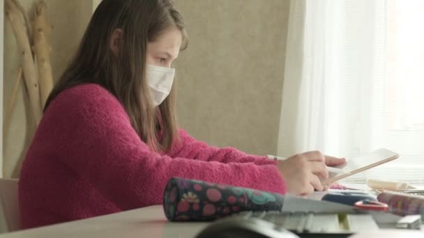 Chica en máscara médica estudiando en casa durante la pandemia de coronavirus — Vídeos de Stock