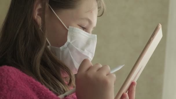 Chica en máscara médica estudiando en casa durante la pandemia de coronavirus — Vídeos de Stock