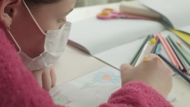Chica en máscara médica estudiando en casa durante la pandemia de coronavirus — Vídeos de Stock