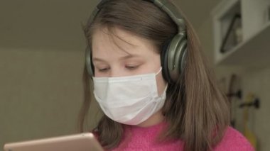Coronavirus salgını sırasında evde çalışan maskeli bir kız.