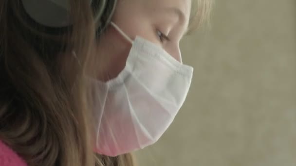 コロナウイルスのパンデミックの間に家で勉強している医療マスクの女の子 — ストック動画