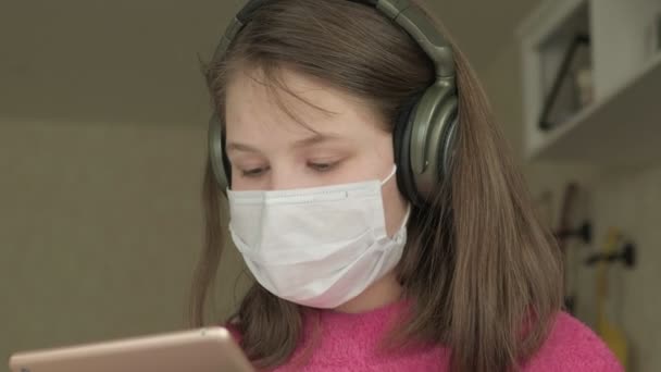 Chica en máscara médica estudiando en casa durante la pandemia de coronavirus — Vídeos de Stock