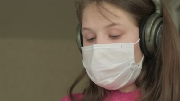 Coronavirus salgını sırasında evde çalışan maskeli bir kız. — Stok video