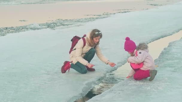 Una mujer con un niño camina sobre un río congelado en la primavera al atardecer . — Vídeos de Stock