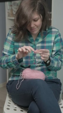 Genç bir kadın örgü örüyor. Dikey video