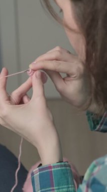 Genç bir kadın örgü örüyor. Dikey video