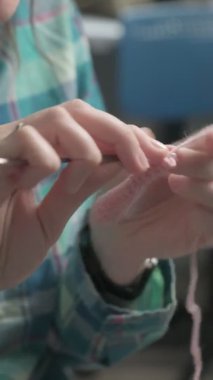 Genç bir kadın örgü örüyor. Dikey video