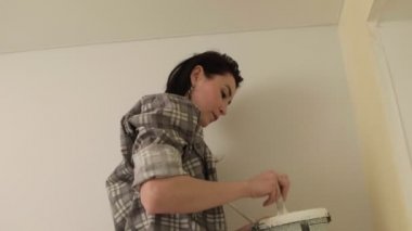 Kadın ev ressamları odadaki duvarları boyuyor..