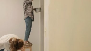 Kadın ev ressamları odadaki duvarları boyuyor..