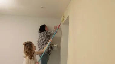 Kadın ev ressamları odadaki duvarları boyuyor..