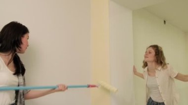 Kadın ev ressamları odadaki duvarları boyuyor..