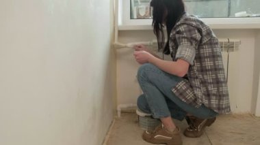 Kadın ev ressamları odadaki duvarları boyuyor..