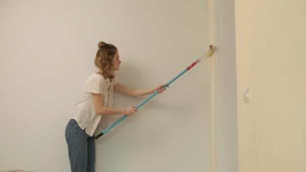 Kvinnliga husmålare målar väggarna i rummet. — Stockvideo