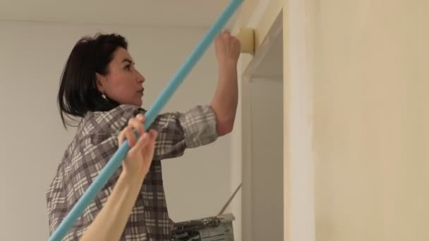 Vrouwelijke huisschilders schilderen de muren in de kamer. — Stockvideo
