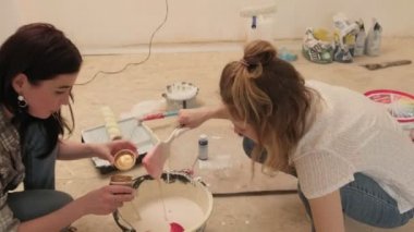 Kadın ev ressamları odadaki duvarları boyuyor..