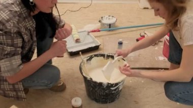 Kadın ev ressamları odadaki duvarları boyuyor..