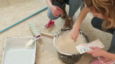 Kadın ev ressamları odadaki duvarları boyuyor..