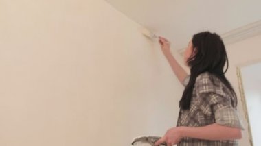 Kadın ev ressamları odadaki duvarları boyuyor..