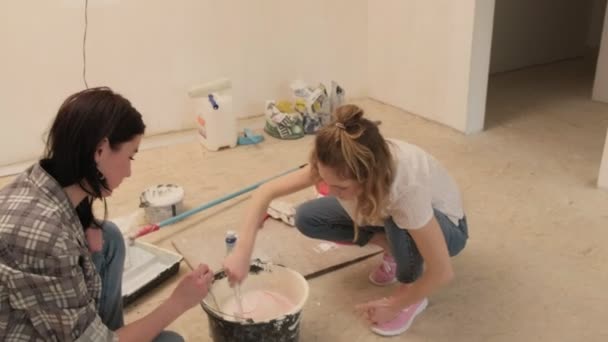 Жіночий будинок художники фарбують стіни в кімнаті . — стокове відео