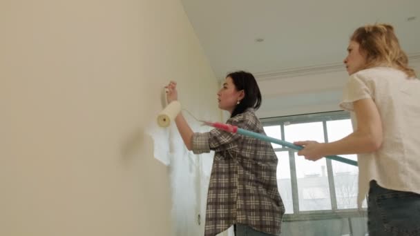 Γυναίκες ζωγράφοι σπιτιών βάφουν τους τοίχους στο δωμάτιο. — Αρχείο Βίντεο