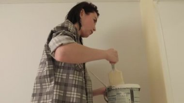 Kadın ev ressamları odadaki duvarları boyuyor..