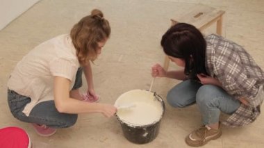 Kadın ev ressamları odadaki duvarları boyuyor..